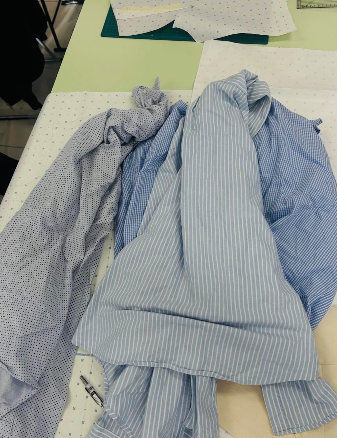 A pile of blue striped and spotted second-hand shirts on a cutting table